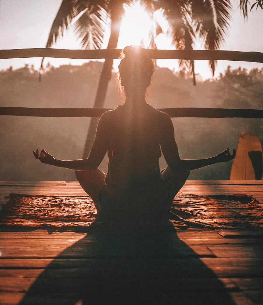 A woman meditating cross-legged at sunrise