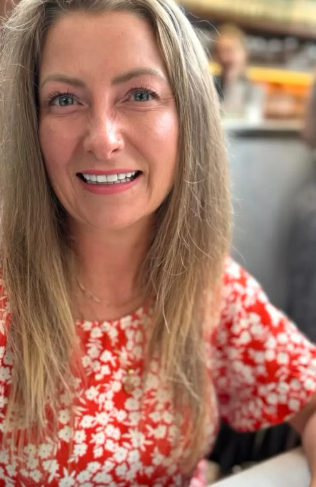 Sam Harrison smiling in a red floral dress