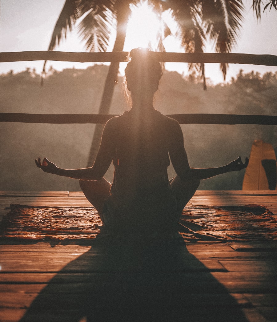 A woman meditating cross-legged at sunrise