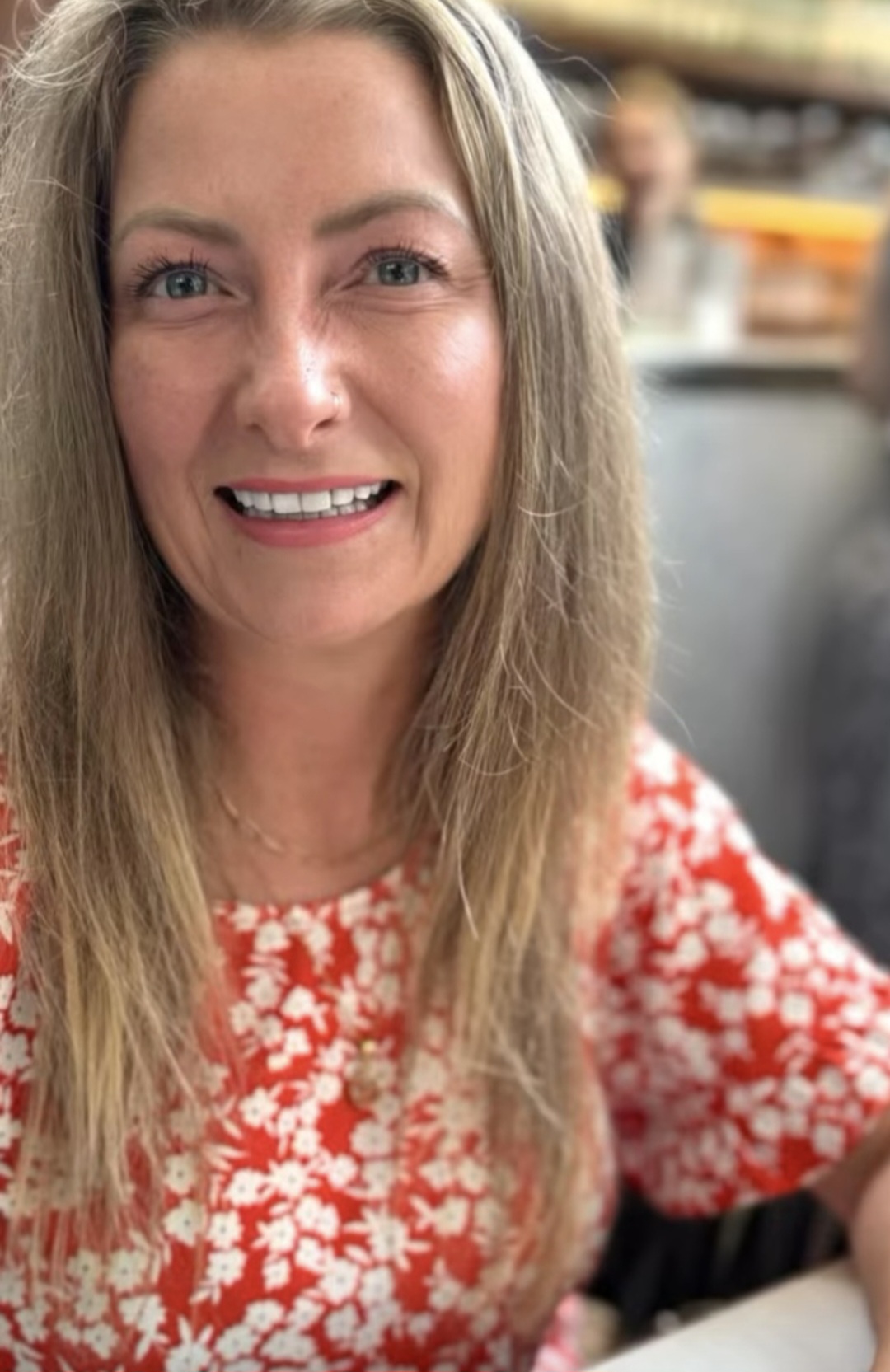 Sam Harrison smiling in a red floral dress